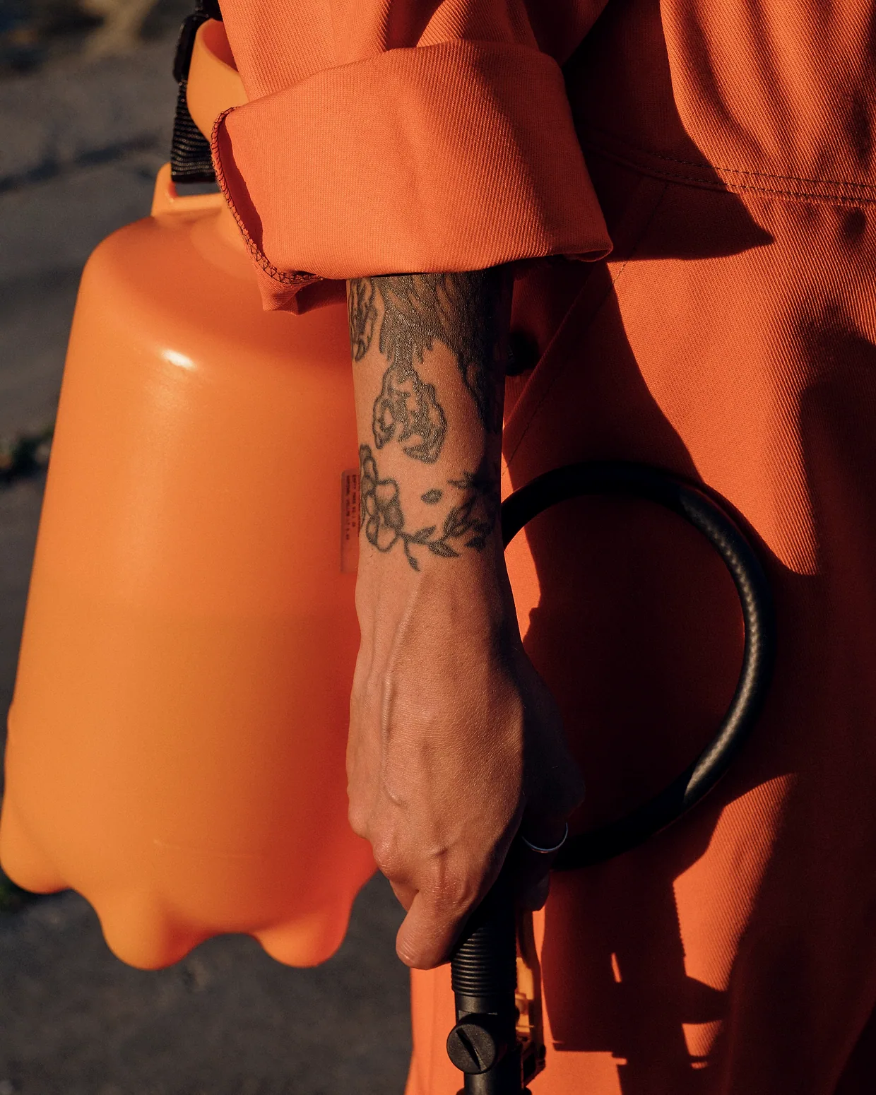 A technician's arm and a pressurised sprayer, close.